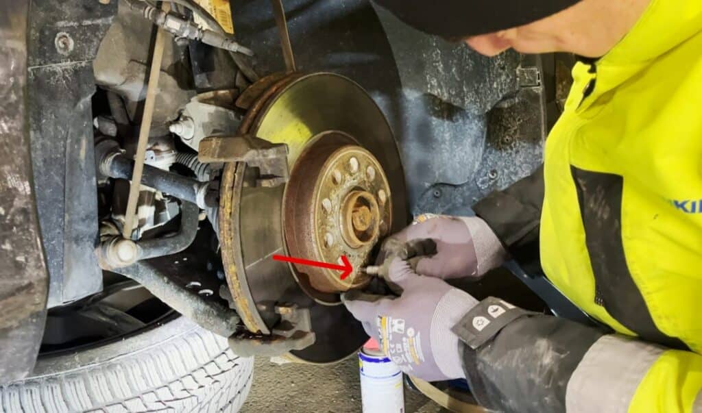 Poluzuj śrubę tarczy hamulcowej Odkręć mocowanie tarczy hamulcowej