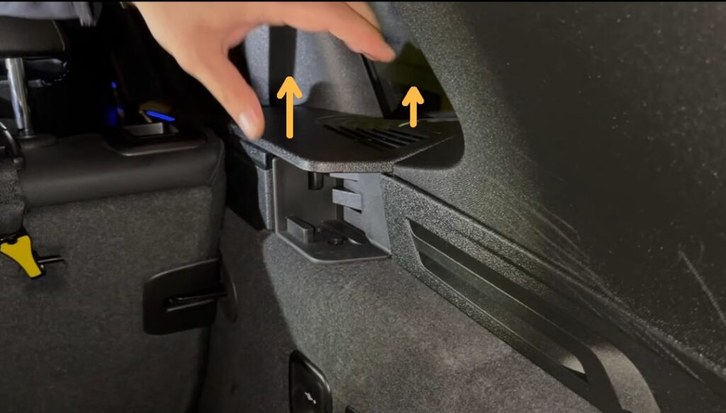 Desengancha la cubierta de la moldura de plástico hacia arriba para retirarla. A continuación, retira la cubierta que rodea el botón de liberación de la cubierta enrollable.